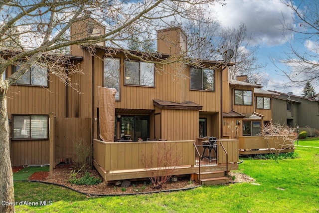 back of house featuring a lawn, a chimney, and a deck