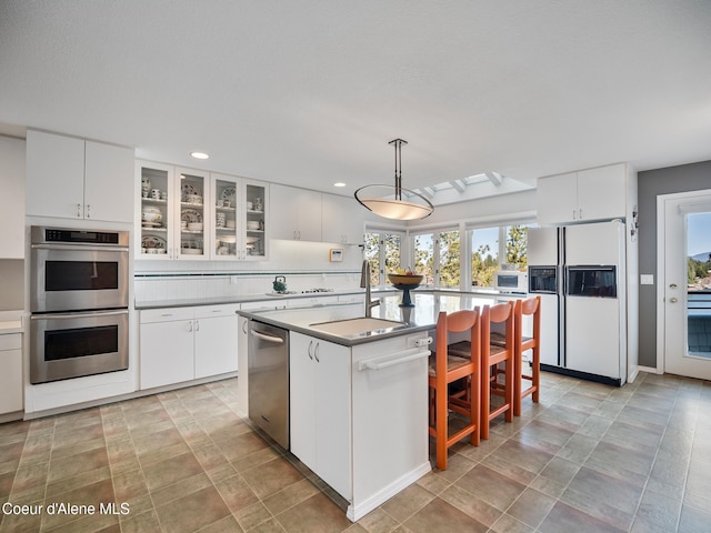 255 S Theresa Terrace Dr, Post Falls, ID 83854 - kitchen with appliances with stainless steel finishes, a sink, white cabinetry, a kitchen island, and glass insert cabinets