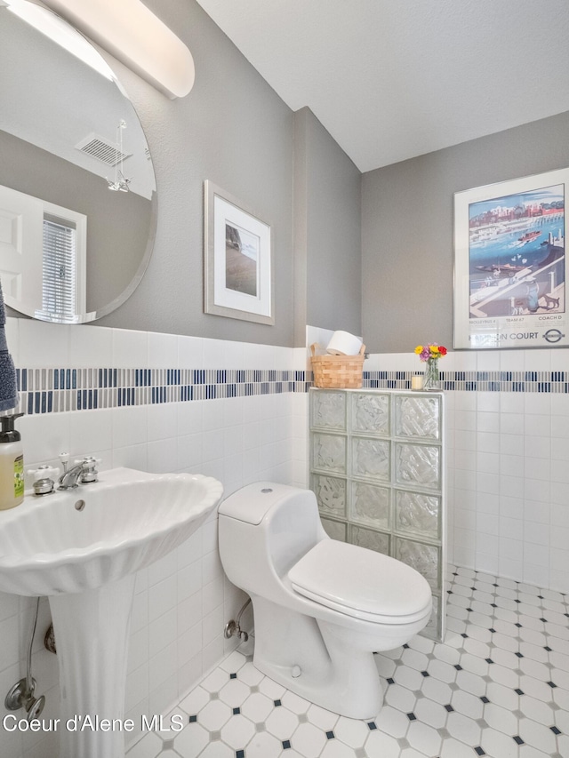 255 S Theresa Terrace Dr, Post Falls, ID 83854 - bathroom with visible vents, wainscoting, toilet, and tile walls