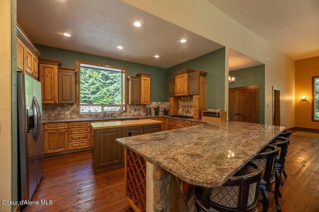131 Long Dr, Priest Lake, ID 83856 - kitchen featuring dark wood-style floors, tasteful backsplash, and stainless steel fridge with ice dispenser