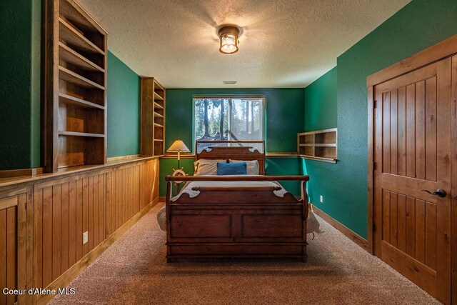 131 Long Dr, Priest Lake, ID 83856 - carpeted bedroom with wood walls and a textured ceiling