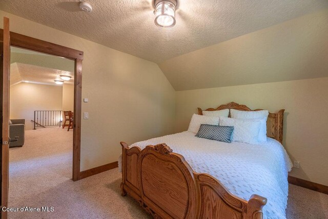 131 Long Dr, Priest Lake, ID 83856 - bedroom featuring a textured ceiling, vaulted ceiling, light colored carpet, and baseboards