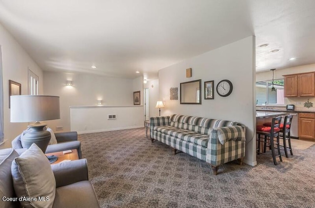 carpeted living area featuring baseboards, visible vents, recessed lighting, and a sink