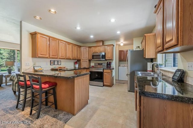 kitchen featuring a peninsula, a breakfast bar area, a sink, appliances with stainless steel finishes, and recessed lighting