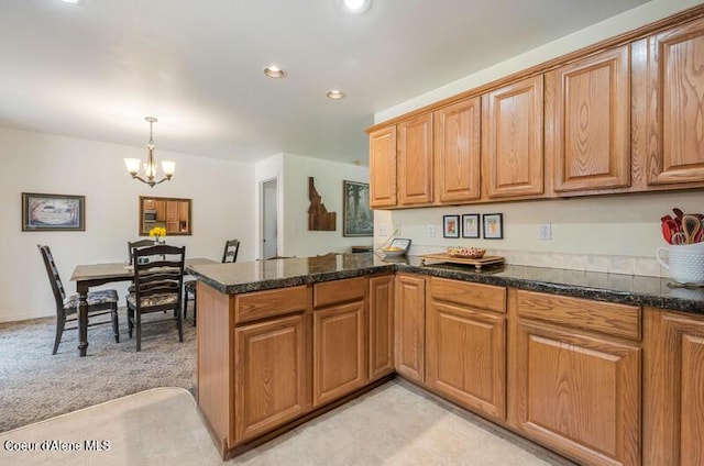 kitchen featuring a peninsula, brown cabinets, recessed lighting, an inviting chandelier, and hanging light fixtures