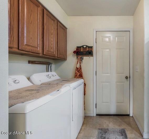 laundry room with cabinet space, washing machine and clothes dryer, light tile patterned floors, and baseboards