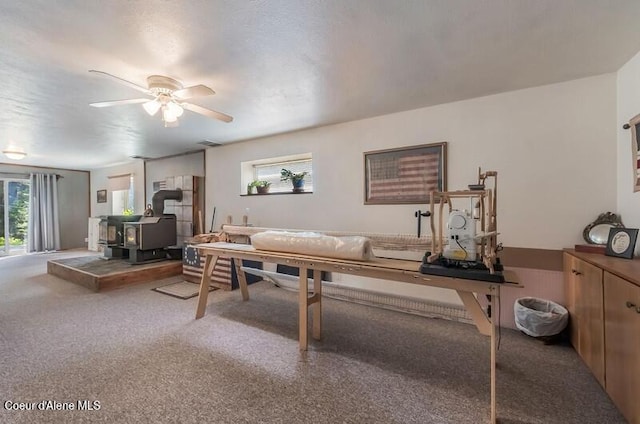 carpeted living room featuring a wood stove, a ceiling fan, and visible vents