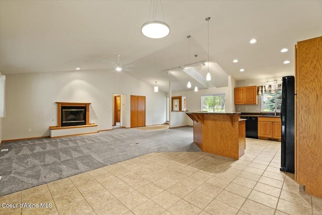 kitchen featuring black appliances, light colored carpet, a breakfast bar area, dark countertops, and vaulted ceiling