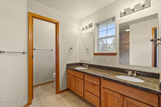 bathroom featuring toilet and double vanity