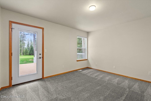 carpeted empty room featuring baseboards