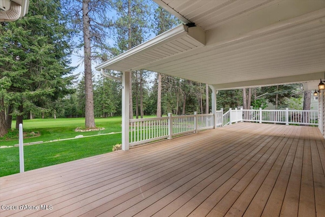 wooden deck with a lawn and view of wooded area