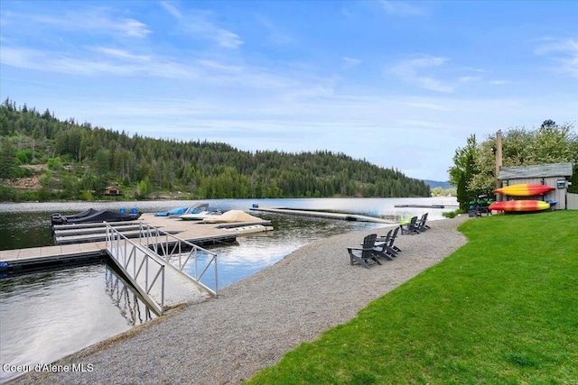 dock with a view of trees, a water view, and a lawn