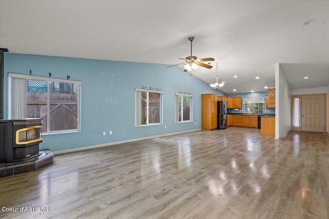 32350 N 7th Ave, Spirit Lake, ID 83869 - unfurnished living room with a wood stove, vaulted ceiling, a chandelier, a ceiling fan, and light wood-type flooring