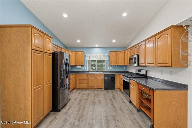 32350 N 7th Ave, Spirit Lake, ID 83869 - kitchen with black appliances, vaulted ceiling, dark countertops, light wood-style flooring, and brown cabinetry