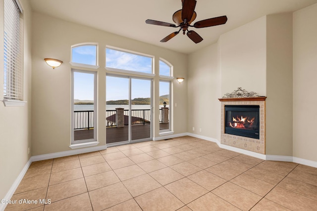 1100 S Division Ave, Sandpoint, ID 83864 - unfurnished living room featuring a tile fireplace, a water view, a ceiling fan, and light tile patterned floors