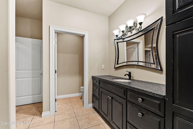 1100 S Division Ave, Sandpoint, ID 83864 - bathroom featuring tile patterned floors, toilet, vanity, baseboards, and a notable chandelier