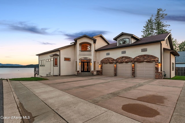 1100 S Division Ave, Sandpoint, ID 83864 - view of front of property featuring an attached garage, stone siding, a water view, and concrete driveway