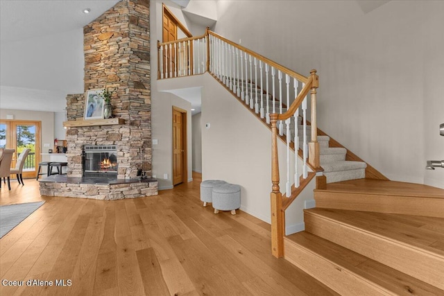 3677 S Capeview Ct, Coeur Dalene, ID 83814 - stairway with baseboards, a stone fireplace, a high ceiling, and hardwood / wood-style flooring