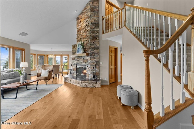 3677 S Capeview Ct, Coeur Dalene, ID 83814 - living room with wood-type flooring, a stone fireplace, high vaulted ceiling, and stairway