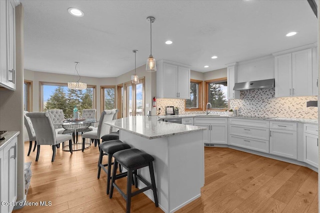 3677 S Capeview Ct, Coeur Dalene, ID 83814 - kitchen with a sink, white cabinets, a breakfast bar, and a healthy amount of sunlight