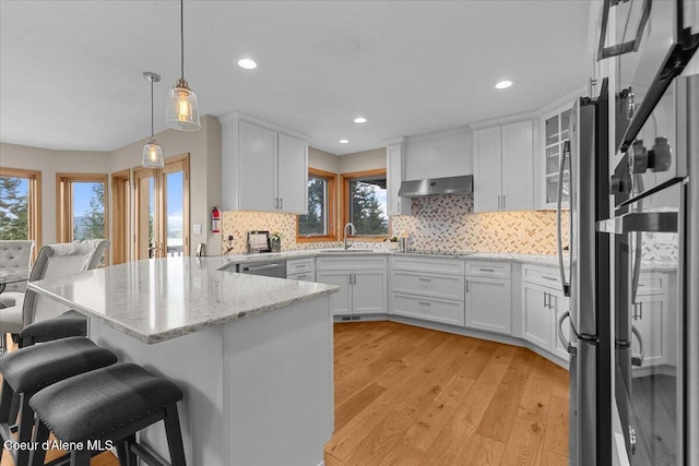 3677 S Capeview Ct, Coeur Dalene, ID 83814 - kitchen with plenty of natural light, a peninsula, under cabinet range hood, and white cabinets