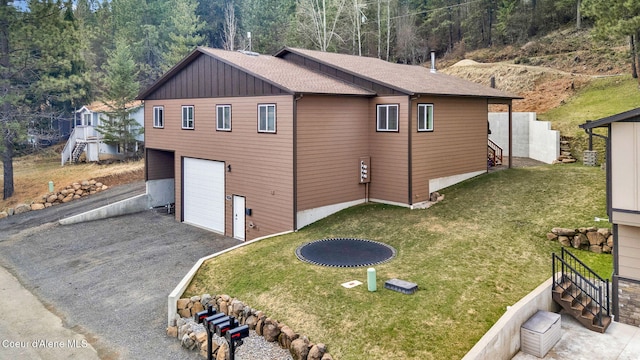 1119 Elm Dr, Saint Maries, ID 83861 - view of home's exterior featuring board and batten siding, aphalt driveway, stairs, an attached garage, and a yard