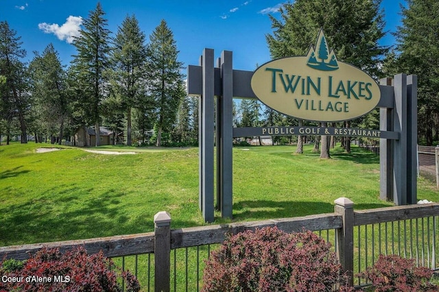 community / neighborhood sign with fence and a lawn