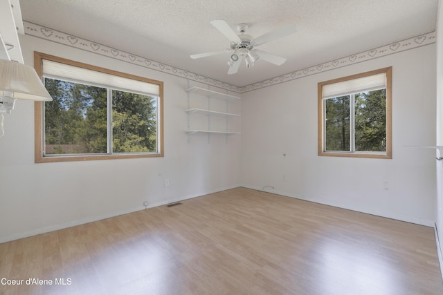 spare room with baseboards, a ceiling fan, a textured ceiling, and light wood-style flooring