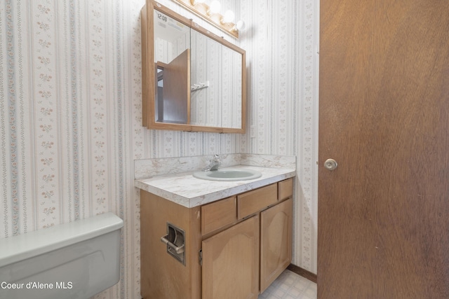half bathroom featuring wallpapered walls, toilet, and vanity