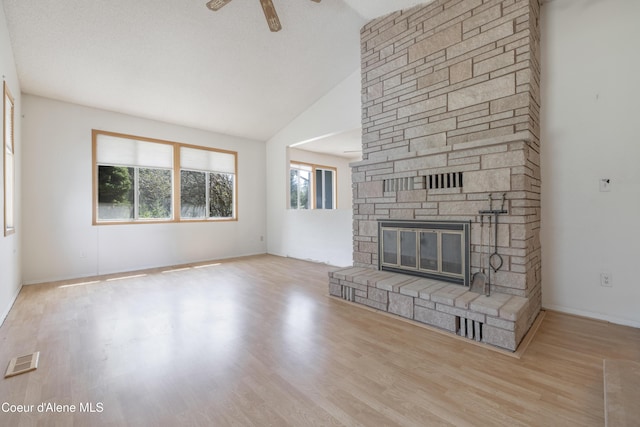 unfurnished living room featuring a fireplace, wood finished floors, a ceiling fan, visible vents, and lofted ceiling