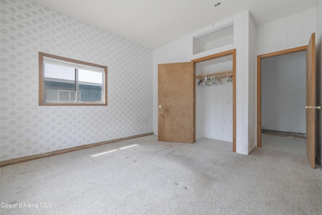 unfurnished bedroom featuring wallpapered walls, carpet floors, and vaulted ceiling