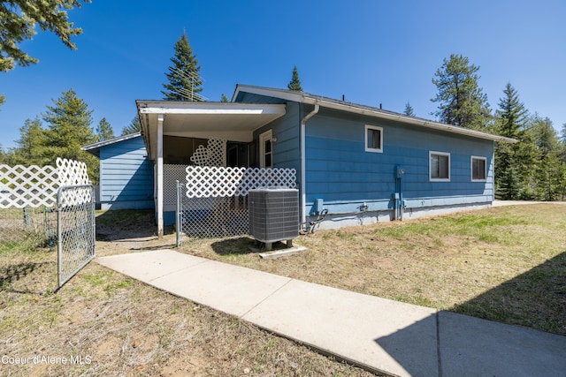 view of home's exterior featuring a lawn, central air condition unit, and fence
