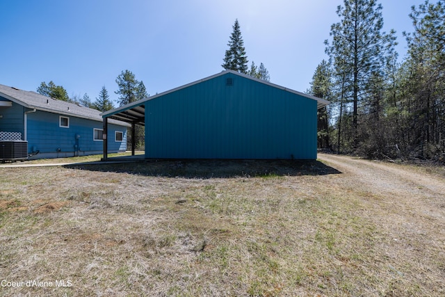 exterior space featuring a carport, central AC unit, and an outbuilding