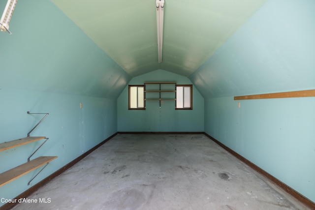 additional living space featuring baseboards, lofted ceiling, and unfinished concrete floors
