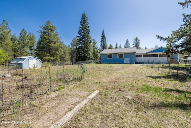 view of yard with a storage unit, fence, and an outbuilding