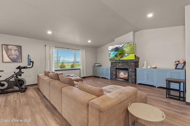 living area with light wood-style floors, a stone fireplace, recessed lighting, baseboards, and vaulted ceiling