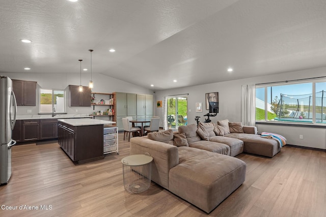 living room featuring recessed lighting, plenty of natural light, vaulted ceiling, and light wood finished floors