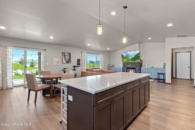 kitchen with dark brown cabinets, open floor plan, visible vents, and light wood-style floors