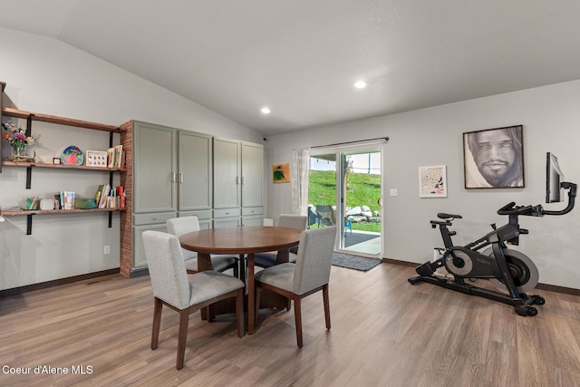 dining area with baseboards, vaulted ceiling, and light wood-style floors