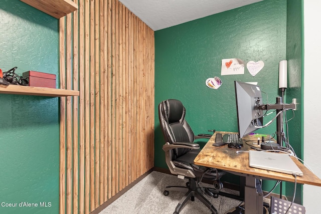 carpeted office featuring a textured ceiling, a textured wall, and baseboards