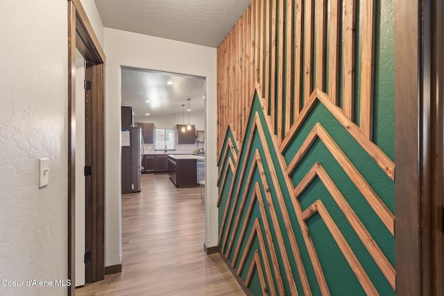 hallway featuring light wood-style floors and a textured ceiling
