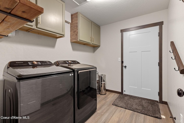 laundry area with baseboards, light wood-style flooring, washing machine and dryer, and cabinet space