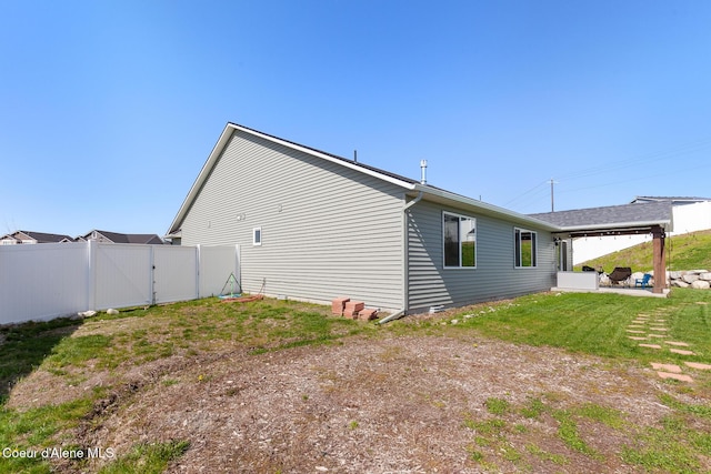 view of property exterior with fence, a gate, a yard, and a patio area