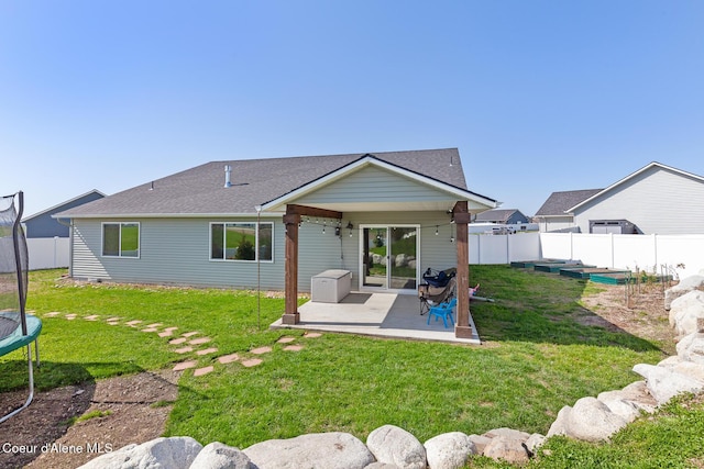 back of house with a fenced backyard, a trampoline, a lawn, and a patio