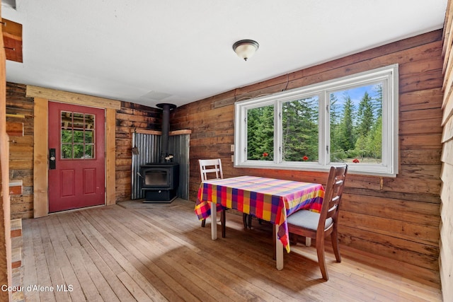 dining area featuring wood walls, a wood stove, and light wood-style floors