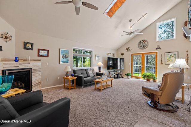 living room featuring a glass covered fireplace, ceiling fan, high vaulted ceiling, and carpet floors