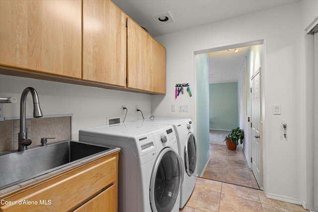 washroom featuring baseboards, cabinet space, washer and clothes dryer, and a sink
