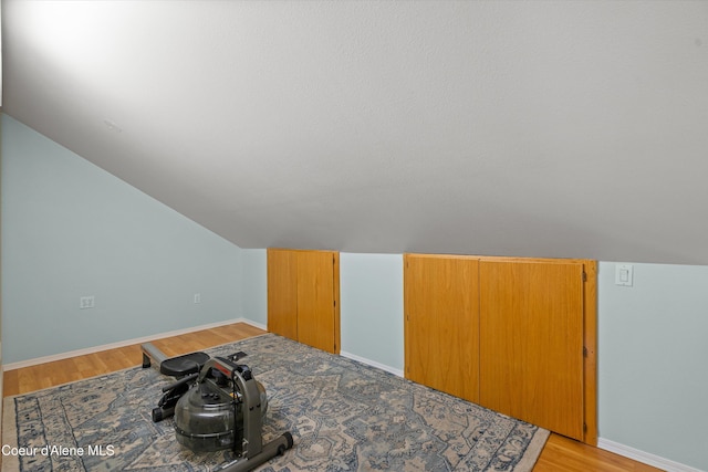 bonus room with baseboards, vaulted ceiling, and light wood-style floors