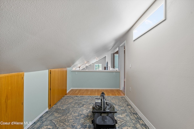 bonus room featuring light wood-style floors, baseboards, and a textured ceiling