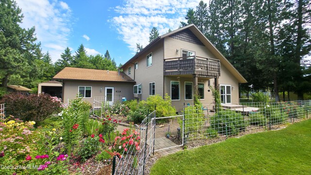 16691 W Hollister Hills Dr, Hauser, ID 83854 - back of property featuring a balcony and a vegetable garden